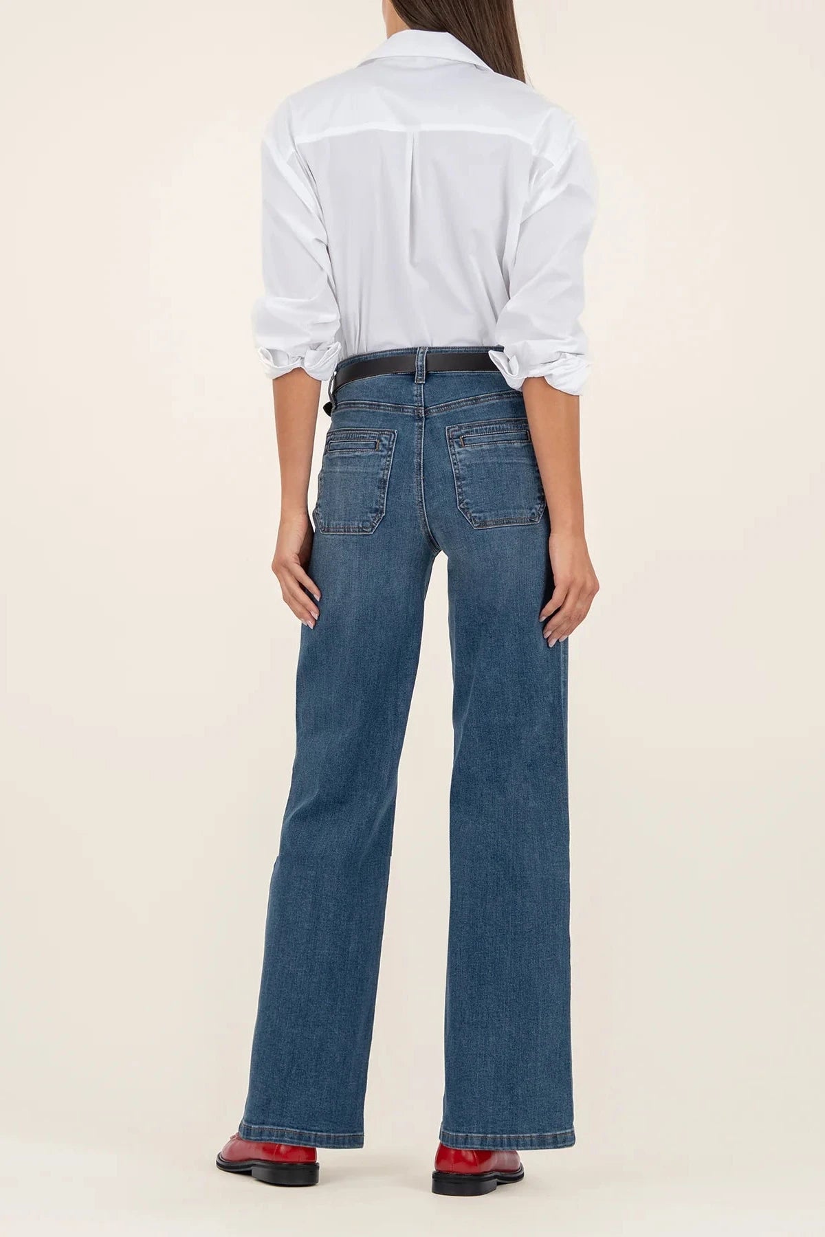 Person wearing a white shirt and blue jeans on a beige background