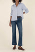 Person wearing a light blue checkered shirt, dark blue jeans, and brown shoes on a beige background
