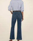 Person wearing a blue striped shirt and dark blue jeans on a beige background