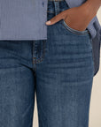 Person wearing blue jeans and a striped shirt with a beige background