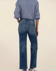 Person wearing a blue denim shirt and jeans on a beige background