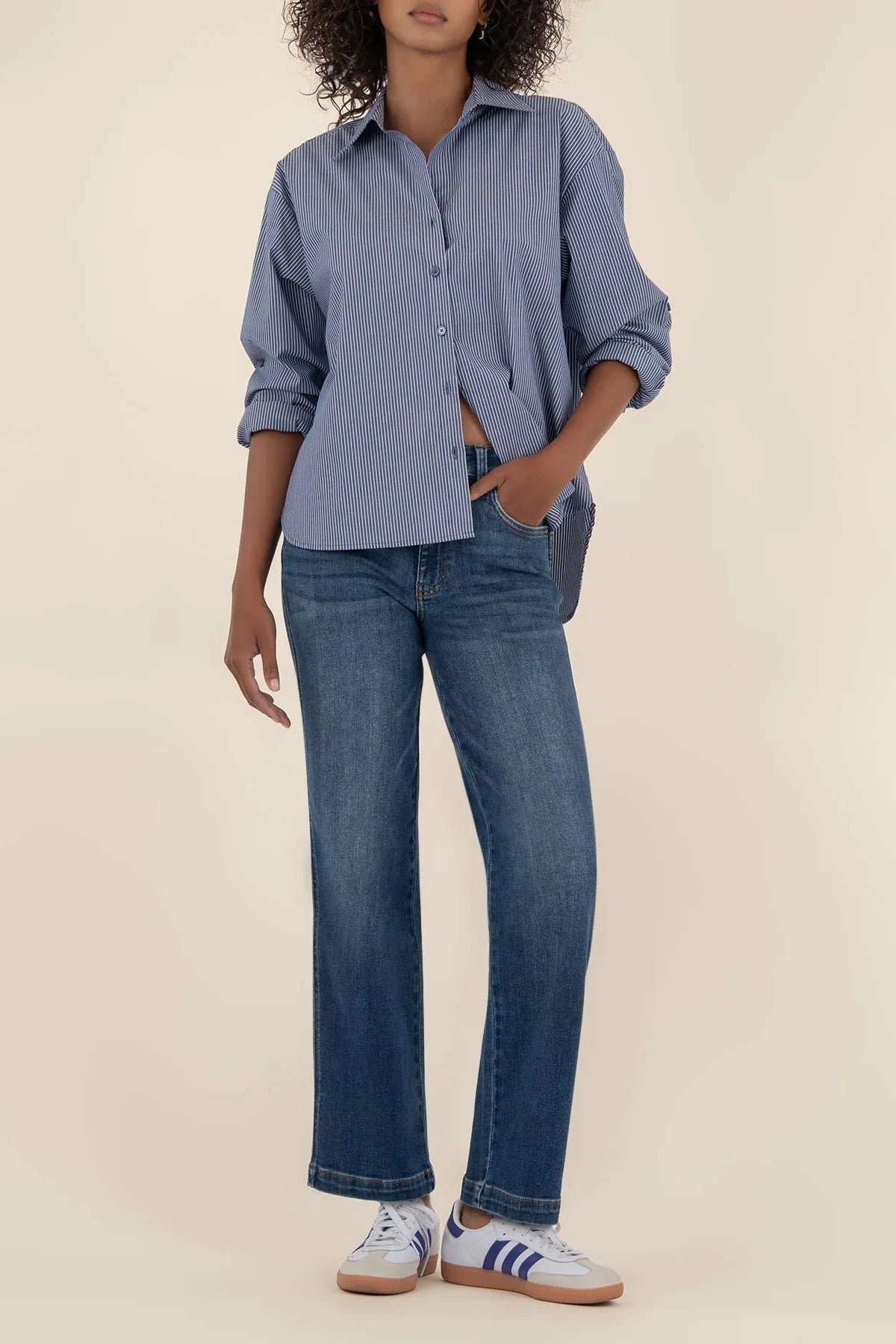 Person wearing a blue shirt and jeans on a beige background