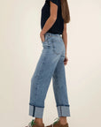 Person wearing light blue jeans and brown shoes on a plain background