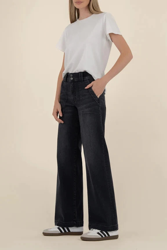 Person wearing black wide-leg jeans and a white t-shirt on a beige background