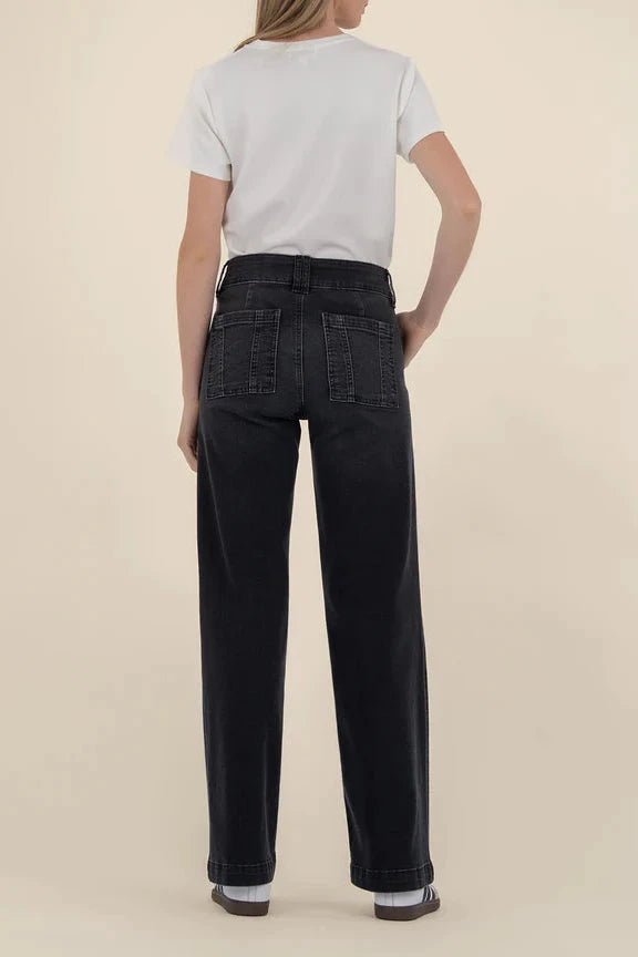 Person wearing black jeans and a white shirt on a beige background