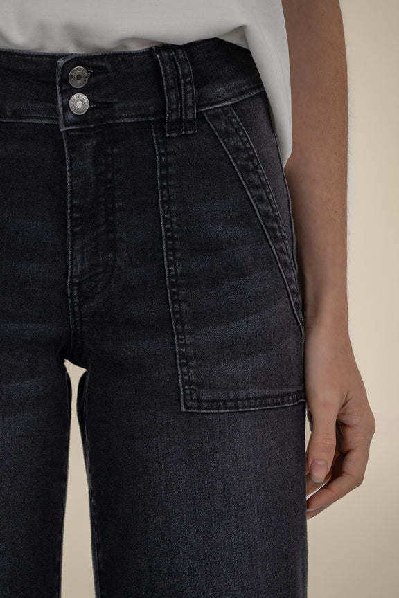 Black denim jeans worn by a person on a beige background