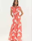 Woman wearing a coral and white patterned dress on a white background