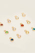 Gold charm pendants with colored gemstones on a beige background