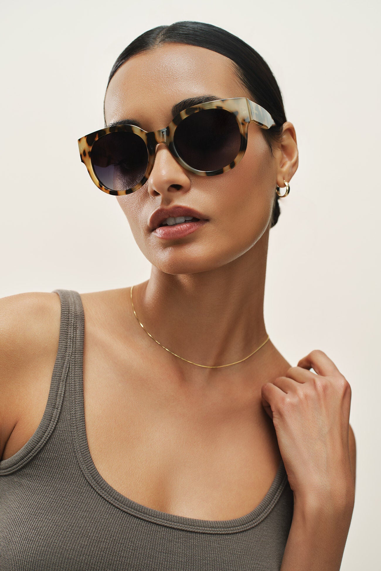 Woman wearing stylish sunglasses with a neutral background