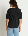 Person wearing a black top and light blue jeans on a plain background