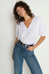 Woman wearing a white top and blue jeans against a plain background
