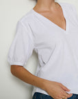Person wearing a white blouse with short sleeves against a plain background