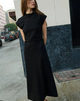 Woman in a black dress standing on a city street.