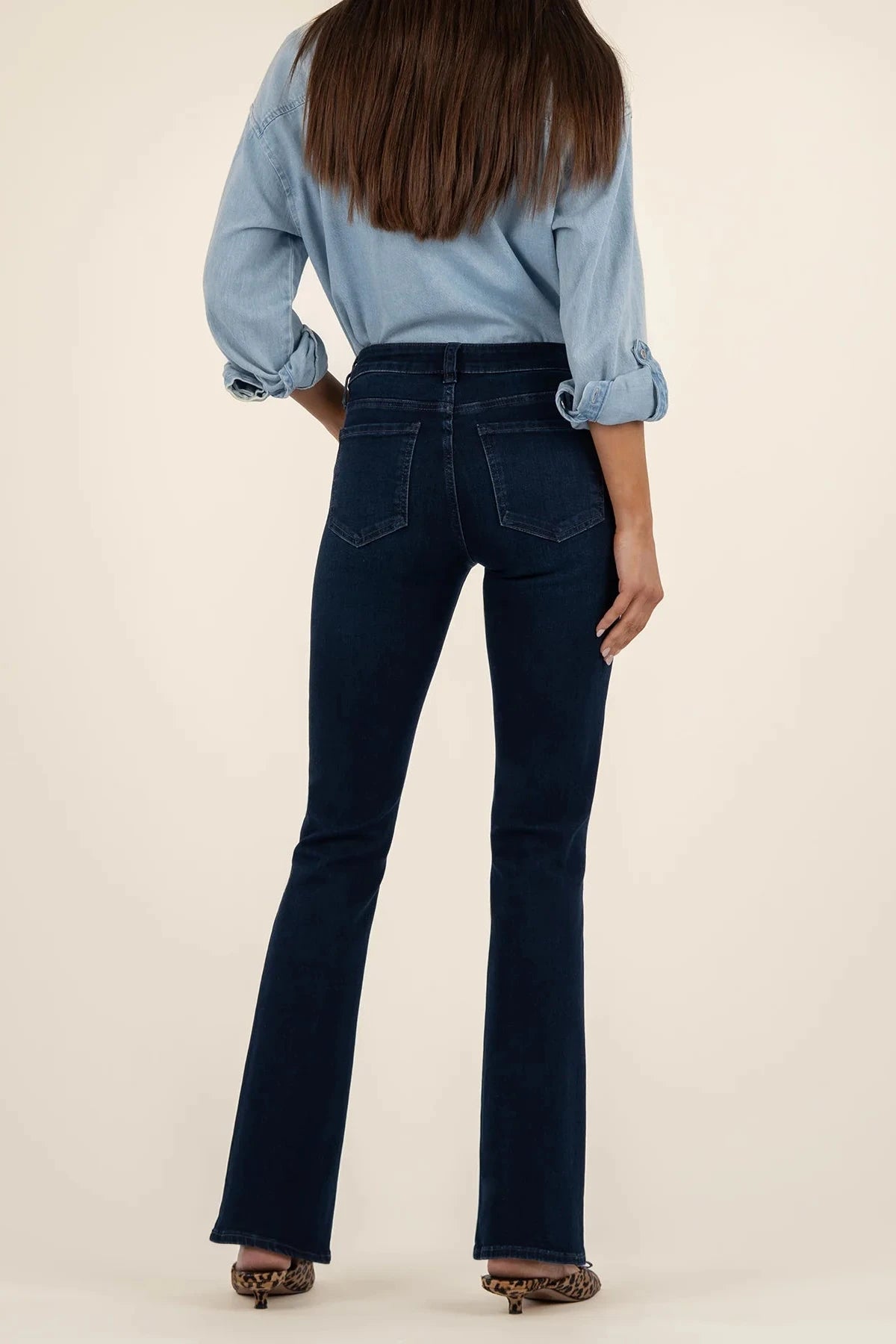 Person wearing blue jeans and a light blue shirt on a beige background