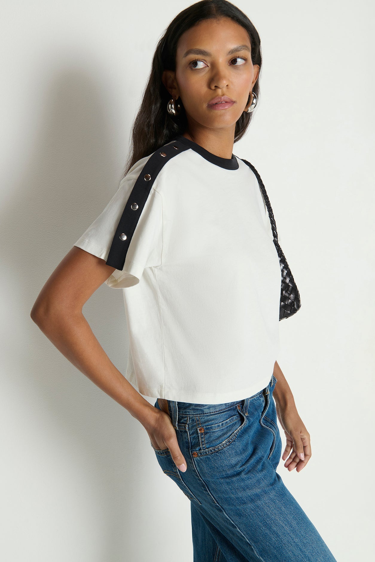 Woman wearing a white t-shirt with black sleeves against a plain background
