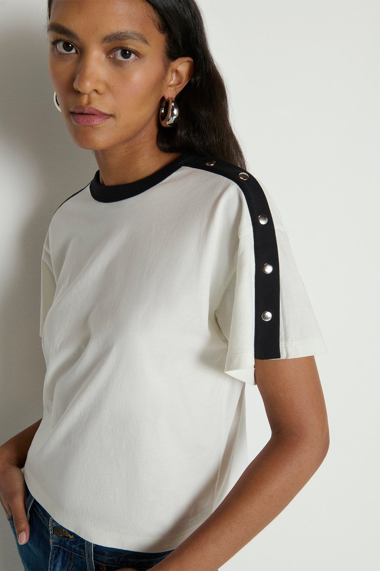 Woman wearing a white t-shirt with black accents on a plain background