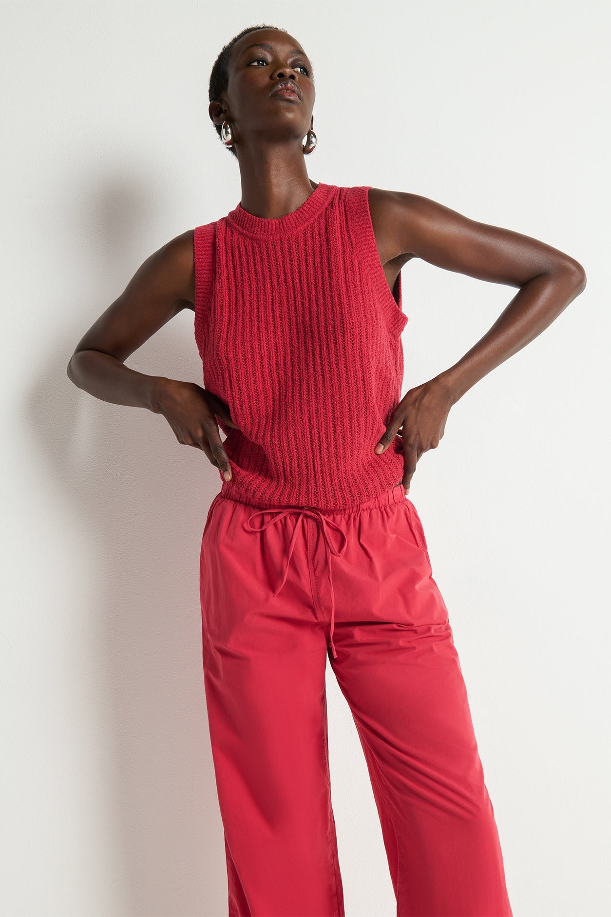 Person wearing a red sleeveless top and pants against a white background
