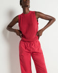 Person wearing a red sleeveless top and pants against a white background