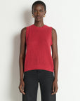 Woman wearing a red sleeveless knitted top against a white background
