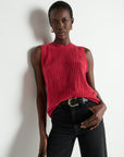 Woman wearing a red sleeveless knitted top against a white background