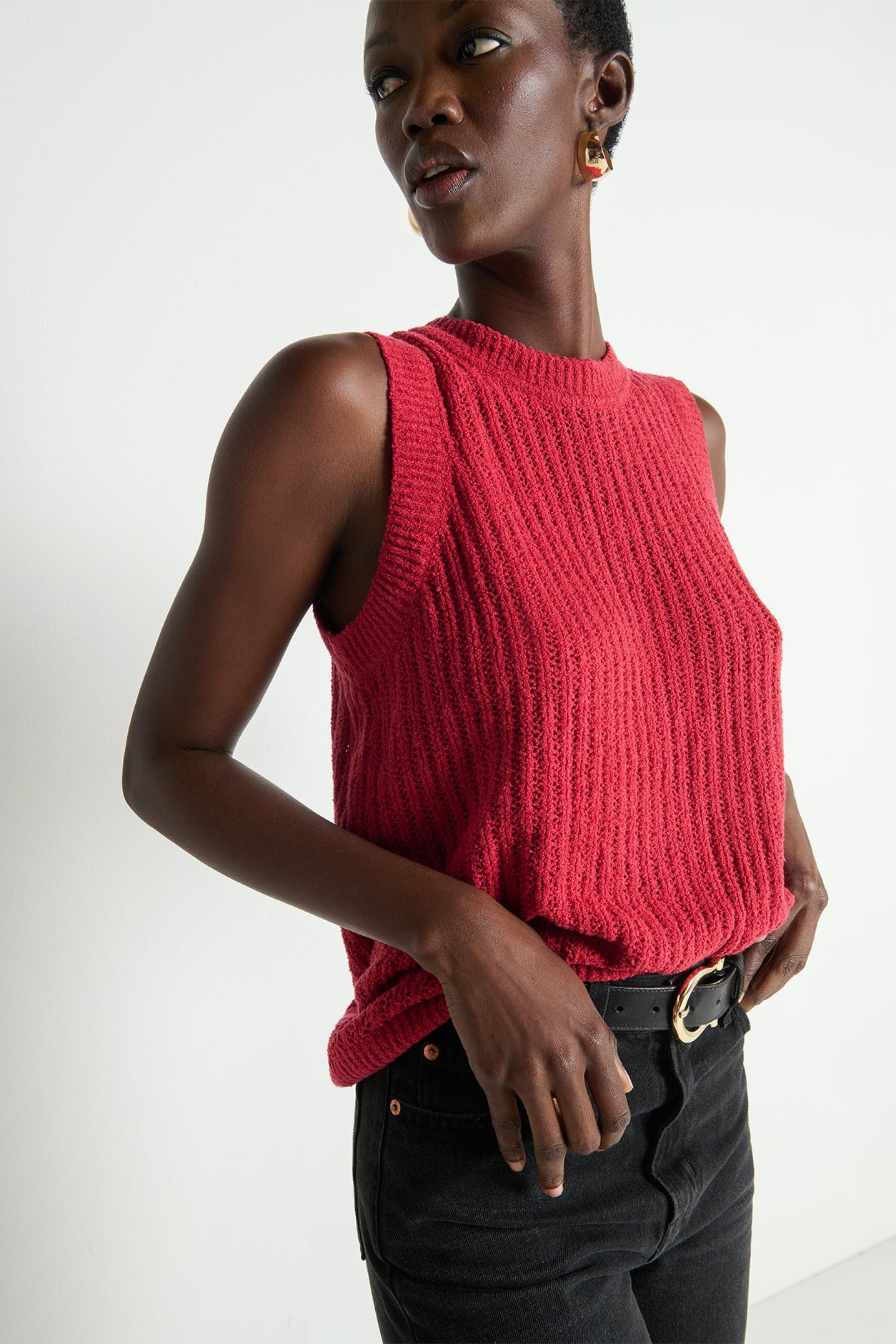 Woman wearing a red knitted sleeveless top against a white background