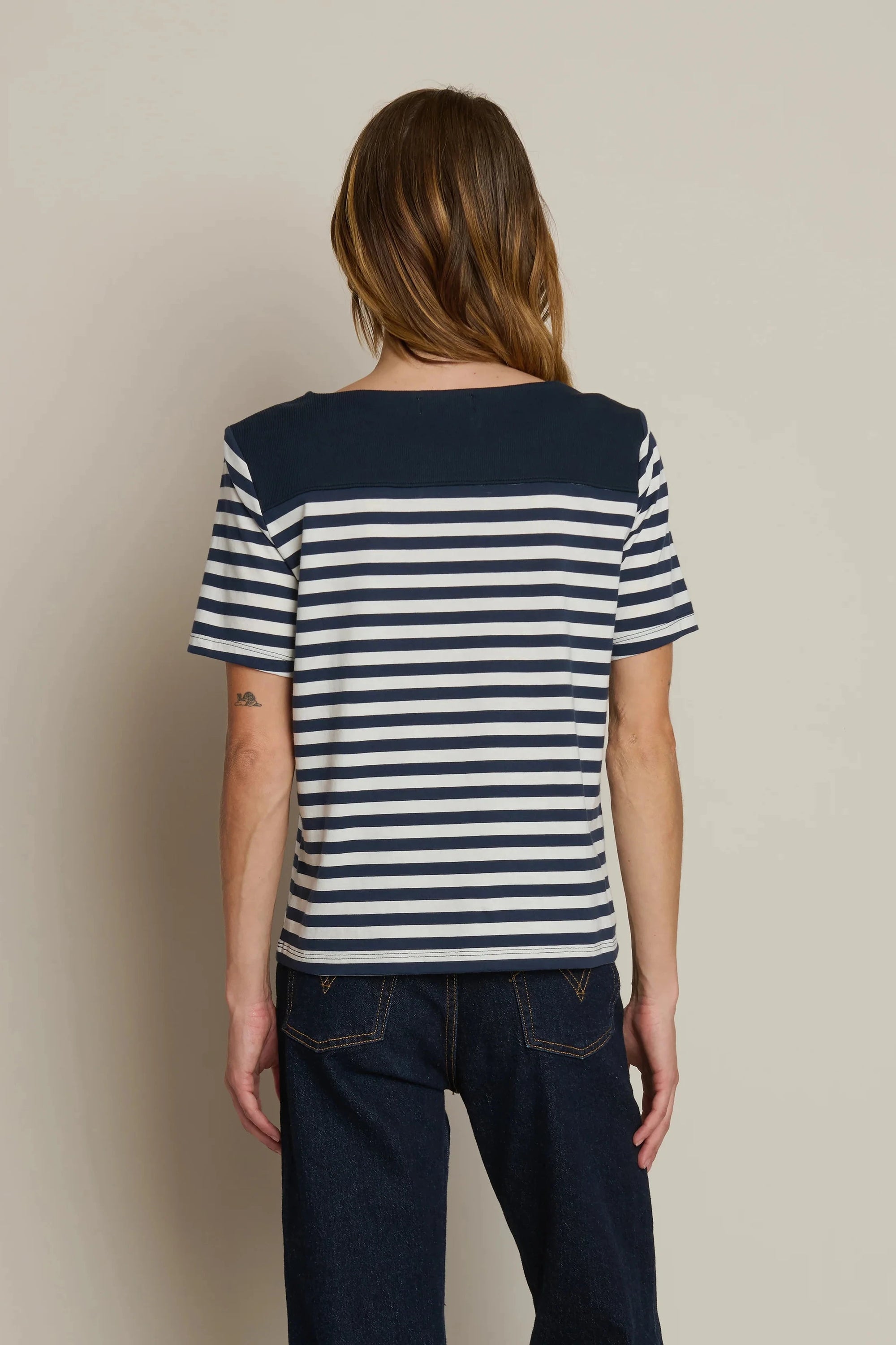 Person wearing a navy and white striped shirt against a beige background