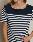 Woman wearing a navy and white striped shirt with button details on a plain background