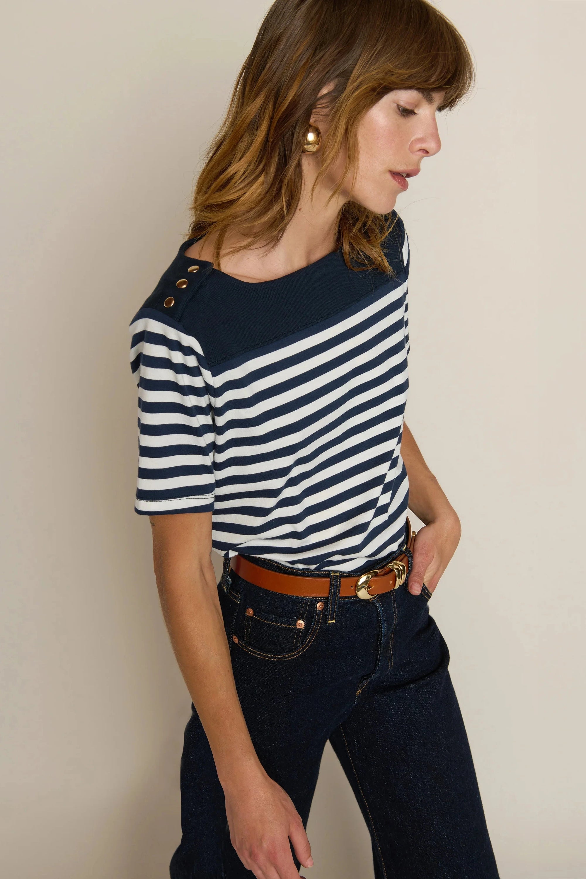 Woman wearing a navy and white striped shirt with a beige background