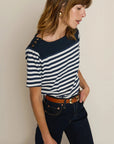 Woman wearing a navy and white striped shirt with a beige background