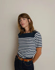 Woman wearing a navy and white striped shirt against a plain background