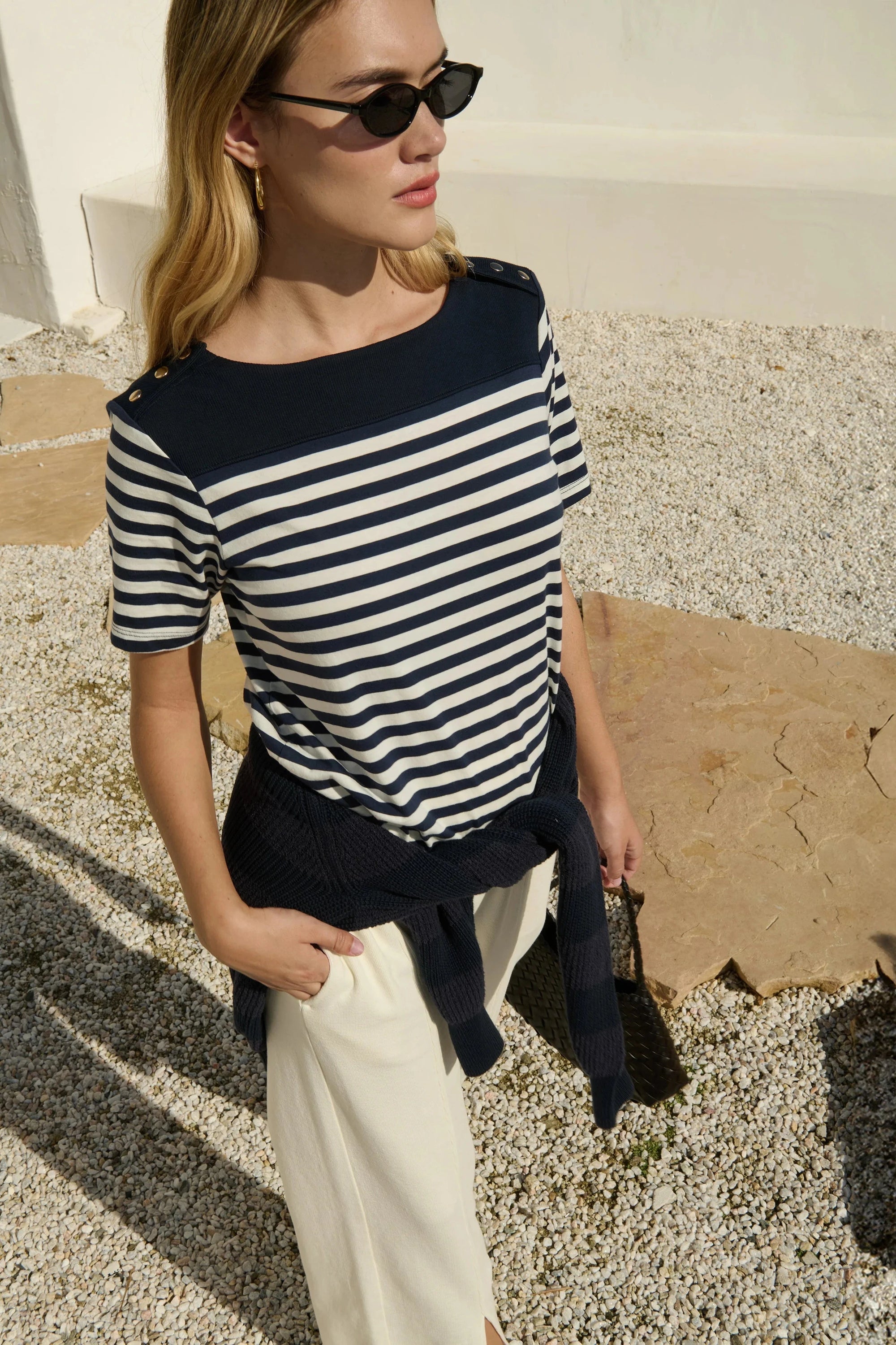 Woman wearing a black and white striped shirt with a navy jacket, standing outdoors.
