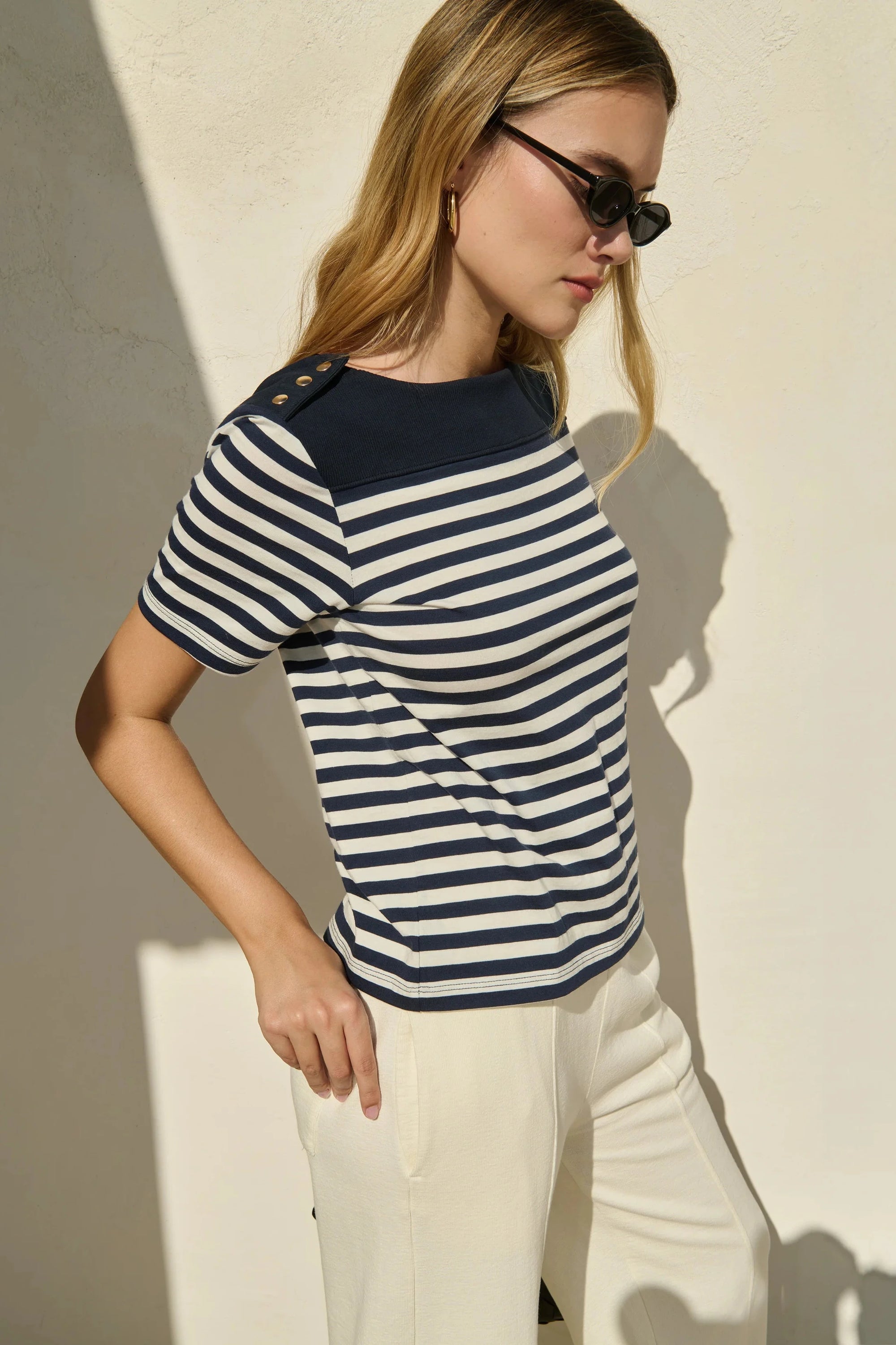 Woman wearing a striped shirt and sunglasses against a neutral background