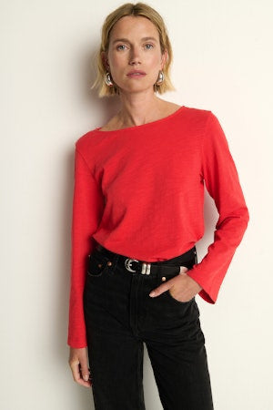 Woman wearing a red sweater and black pants against a white background