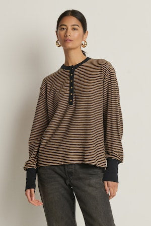 Woman wearing a striped sweater and dark jeans against a plain background