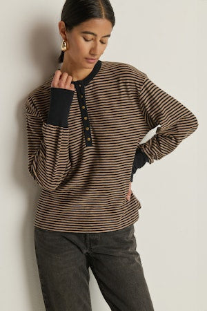 Woman wearing a striped sweater and dark jeans against a plain background
