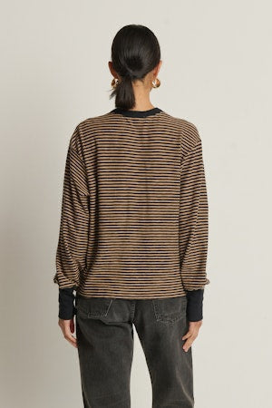 Person wearing a striped sweater and dark pants on a plain background