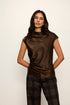 Woman wearing a brown cowl-neck top and plaid pants against a white background
