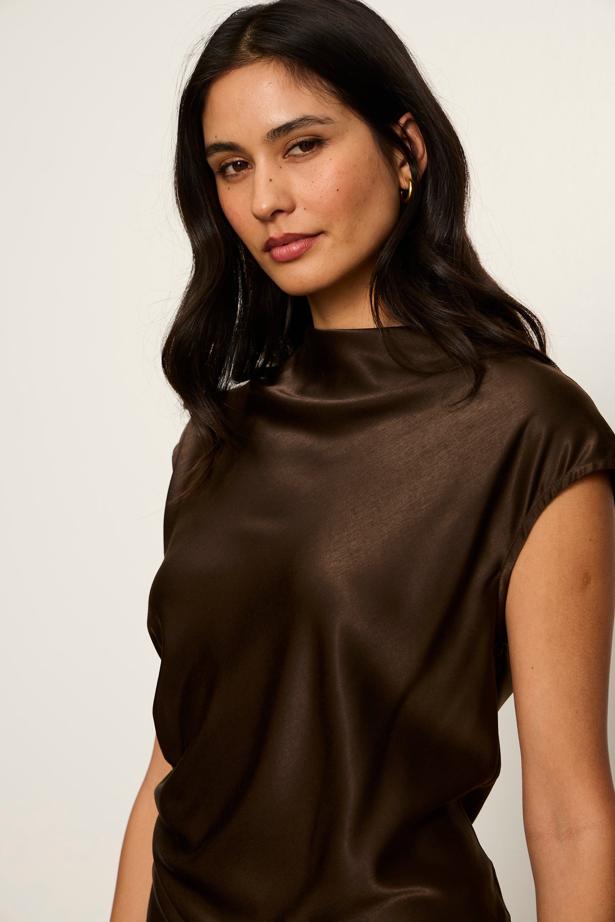 Woman wearing a brown top against a plain background