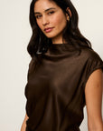 Woman wearing a brown top against a plain background
