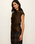 Woman wearing a brown sleeveless top and plaid pants on a white background