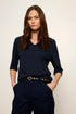 Woman wearing a navy blue outfit with a belt against a plain background