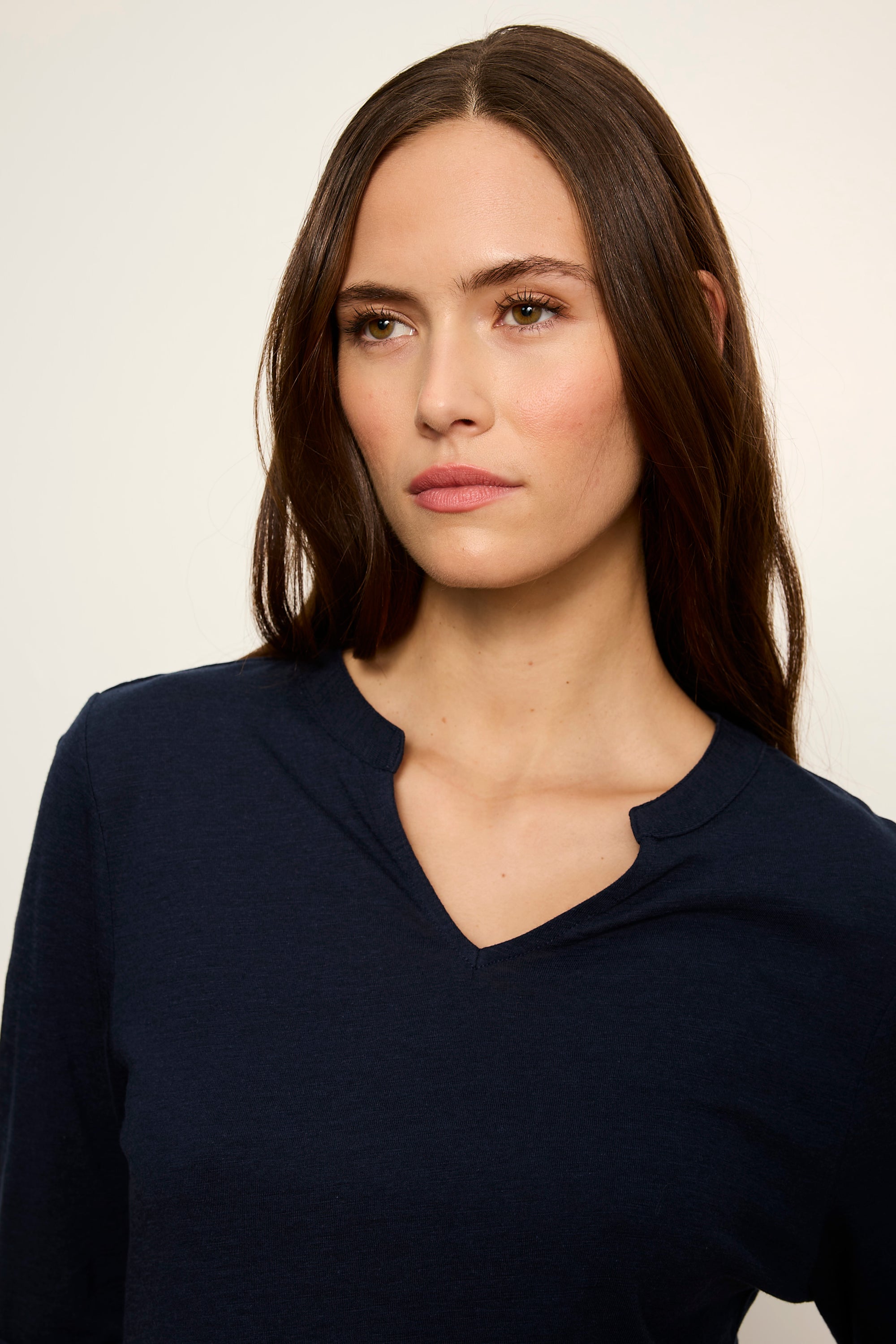 Woman wearing a navy blue top against a plain background