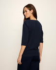 Woman wearing a navy blue outfit against a plain background