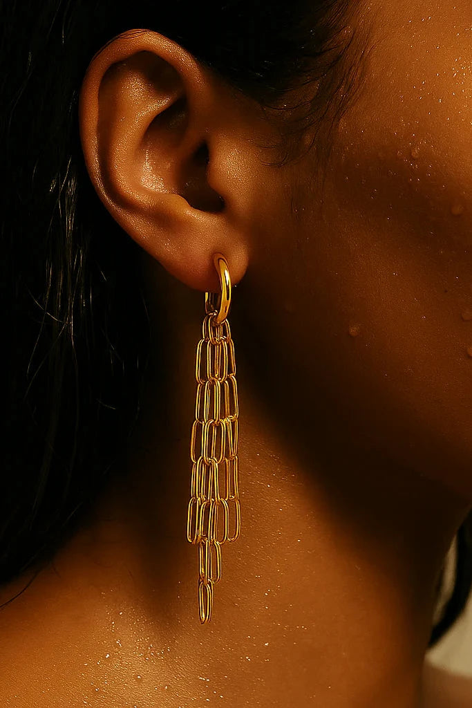 Close-up of a person wearing a gold earring with a neutral background