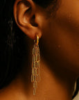 Close-up of a person wearing a gold earring with a neutral background