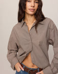 Woman wearing a brown checkered shirt and blue jeans against a plain background