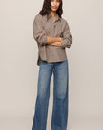Woman wearing a beige shirt and blue jeans on a plain background