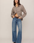 Person wearing a beige shirt and blue jeans on a plain background