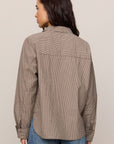 Person wearing a brown checkered shirt and blue jeans against a beige background
