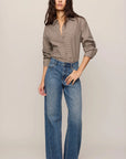 Woman wearing a beige shirt and blue jeans on a plain background